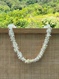 White single tuberose lei hanging from wooden frame